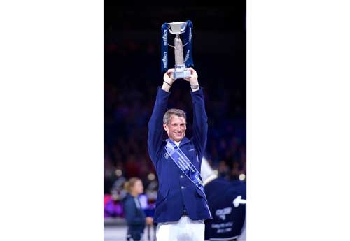 Symphonie en bleu : le cavalier allemand Daniel Deusser brandit le trophée Longines FEI World Cup™ de la victoire à la finale 2014 à Lyon avec Cornet D'Amour (© FEI/Arnd Bronkhorst)